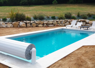 Piscine maçonnée de 10 x 4 m avec membrane gris clair, escalier d’angle et banquette